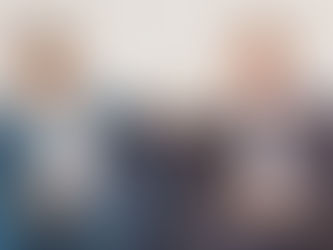 Two men in suits talking on a blue sofa during a LinkedIn video production shoot at a Mayfair office.