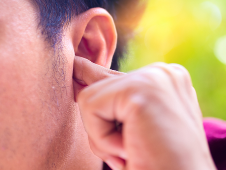 Un joven tiene un tapón de cerumen en el oído y trata de sacarlo con su dedo