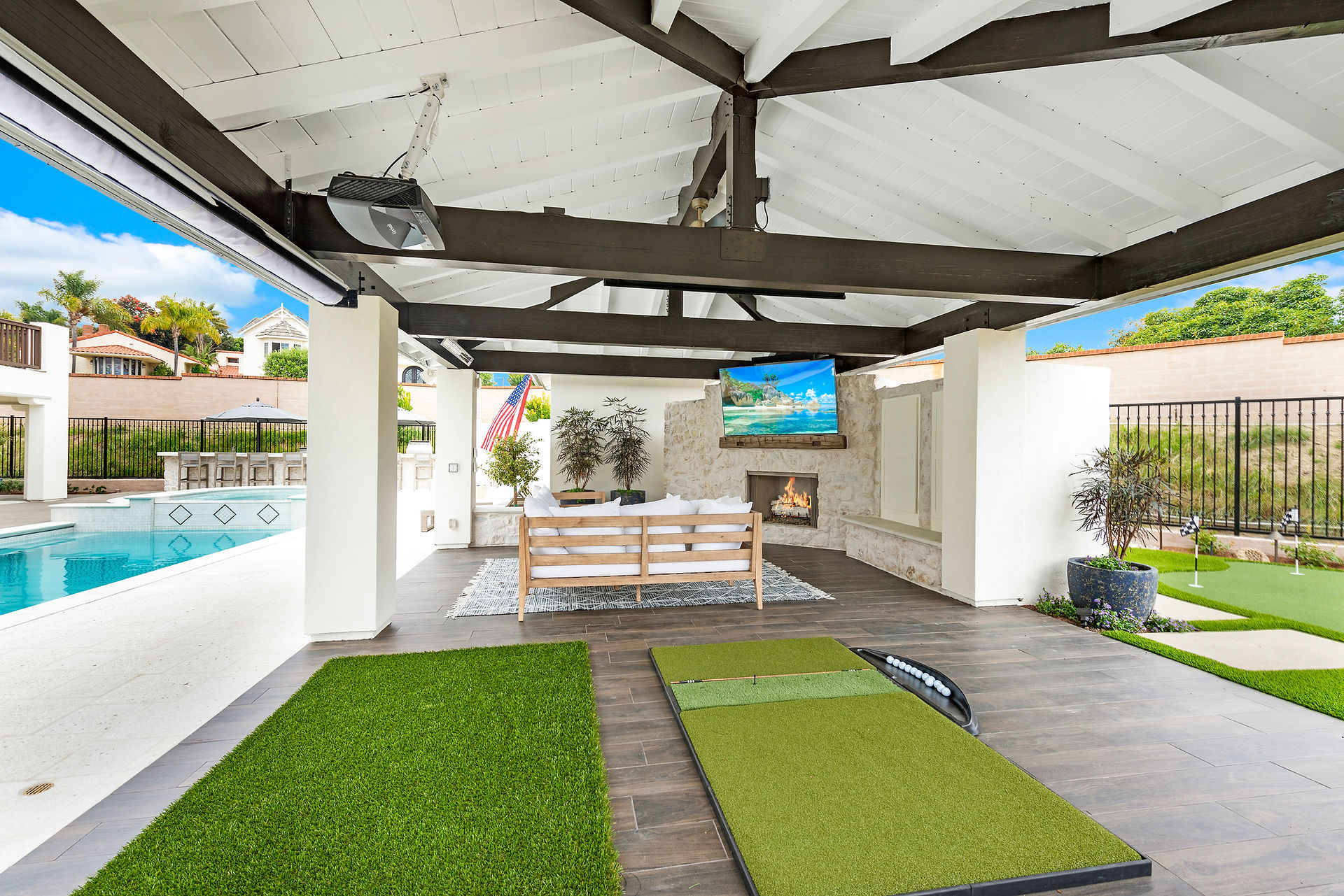 covered patio with flatscreen tv, fireplace, and  putting greens