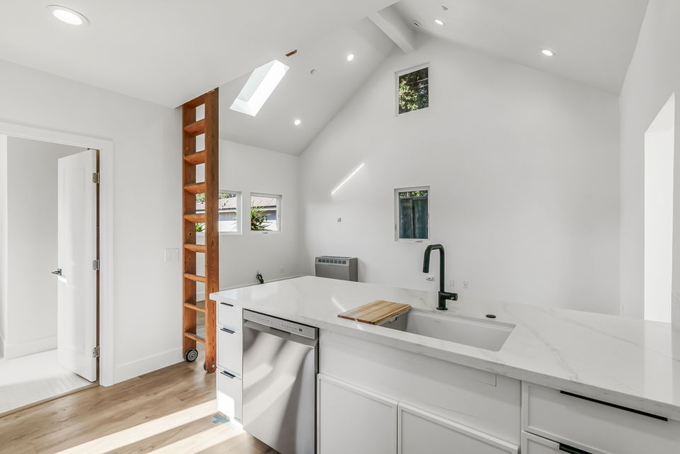 View of kitchen with farm-style sink and view of stairs leading up to loft