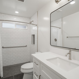 White bathroom with walk-in shower and black flooring