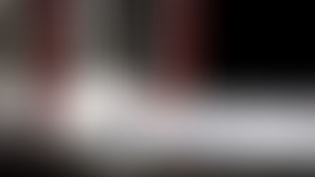 A hockey stick rests against a puck near a red goal net on an ice rink. The setting is dimly lit, highlighting the icy texture.