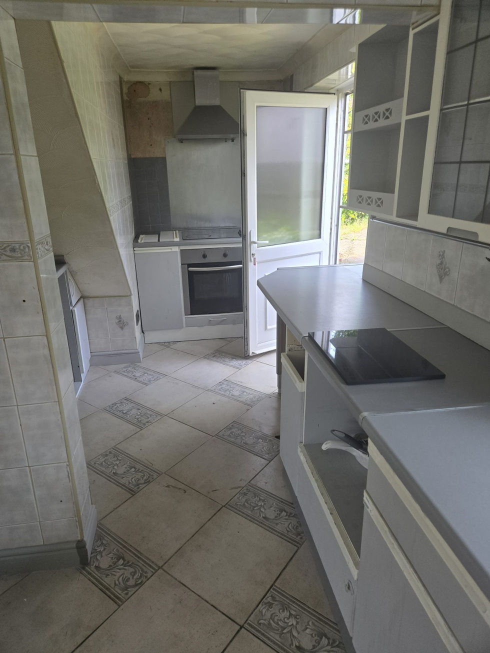 Narrow kitchen with stove, sink, and open door