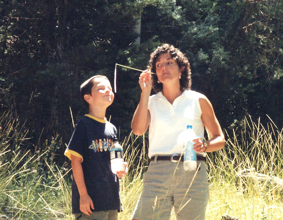 Mom and son outside near woods.