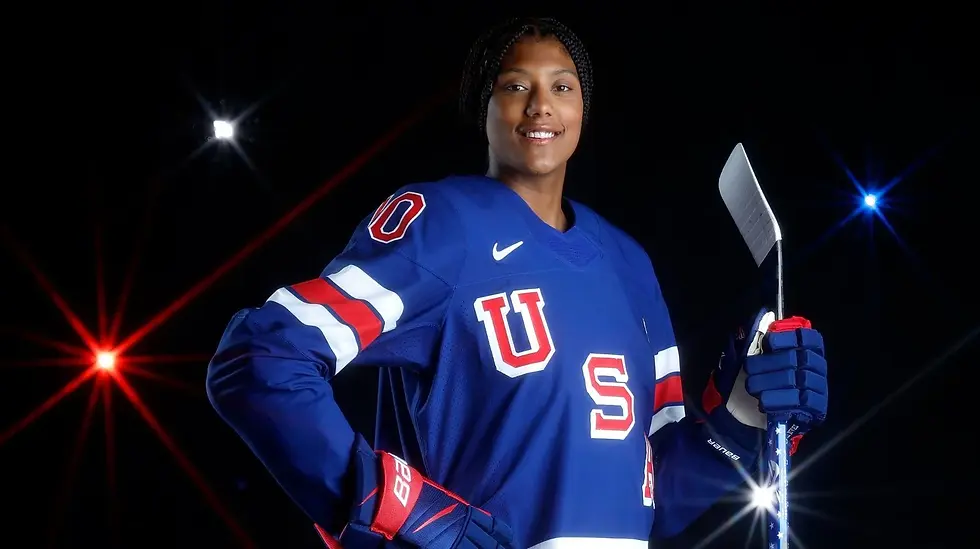 Athlete Laila Edwards in front of a black screen that has twinkling red, white and blue lights, while she is holding a hockey stick. 