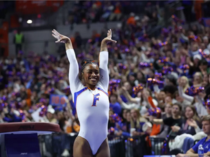 Gymnast Selena Harris-Miranda posing at the end of her routine with her arms in the air. 
