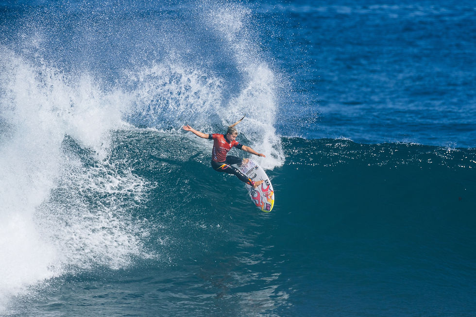 Surfer Erin Brooks riding a wave in the ocean on her surfboard.