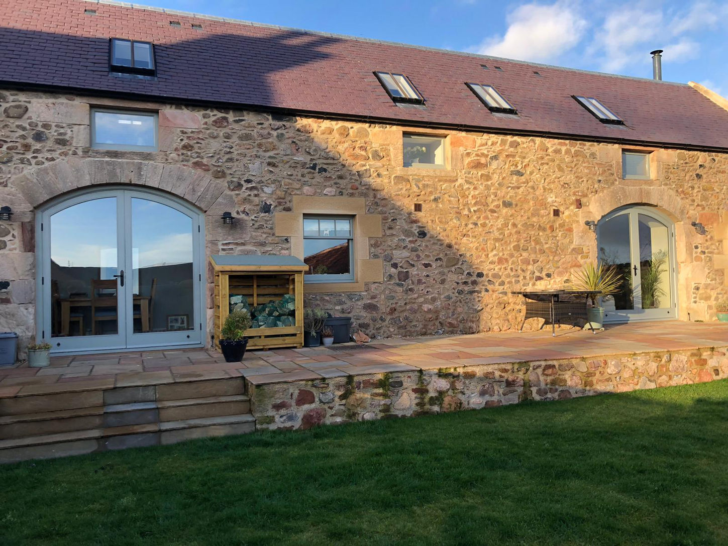 Stone barn conversion with patio and green lawn