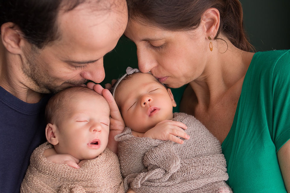 Parents lovingly holding two sleeping babies.