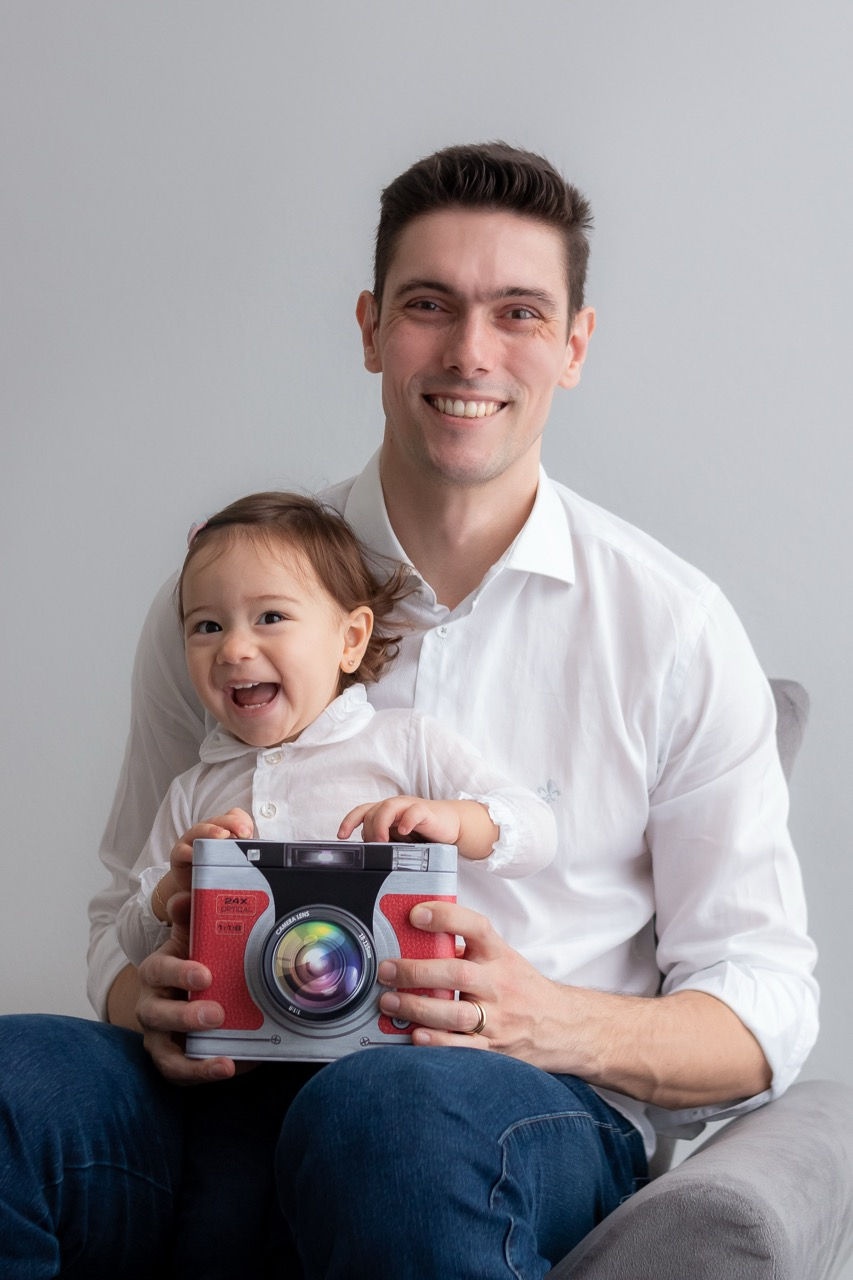 Man and child smiling, holding a large toy camera.