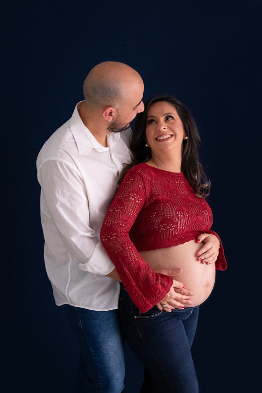 Pregnant couple embracing, woman in red top.