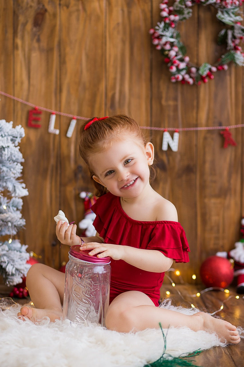 Smiling child in red outfit with festive background.