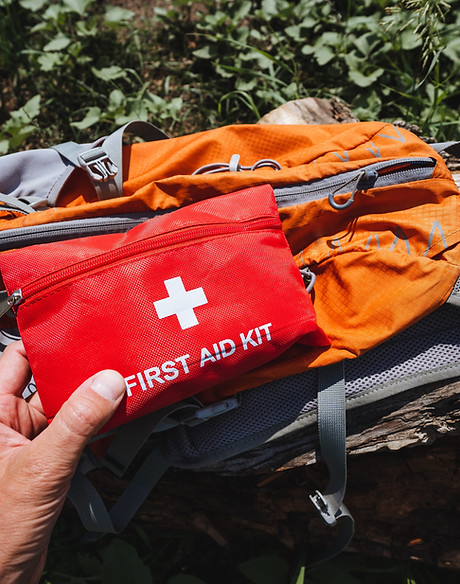 Beside the orange backpack, a person has a first aid kit for emergencies. Personal protect
