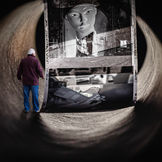 An art photograph depicting a man inside a textured tunnel, observing a large installation of layered analog film. The work represents the meeting of digital photography and analog media, exploring memory as both a physical and temporal space.