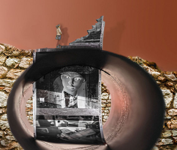 Opera di fine art concettuale: una figura femminile minuscola cammina sopra un rullino fotografico Ilford HP5 tranciato che poggia su un muro di pietra. Il rullino è retroilluminato e crea un tunnel visivo metafisico su sfondo color terracotta.
