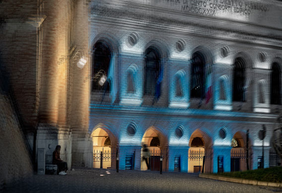 Sferisterio di Macerata in multiesposizione notturna con architettura neoclassica blu, figura seduta e stratificazione temporale.