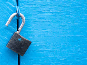 Image: Open pad lock on blue door background. Article: Three Coaching Skills that Unlock Forward Action: Brainstorming, Requesting, and Challenging. Explore how coaching tools like brainstorming, requesting, and challenging deepen learning and forward action—core to the Co-Active approach.