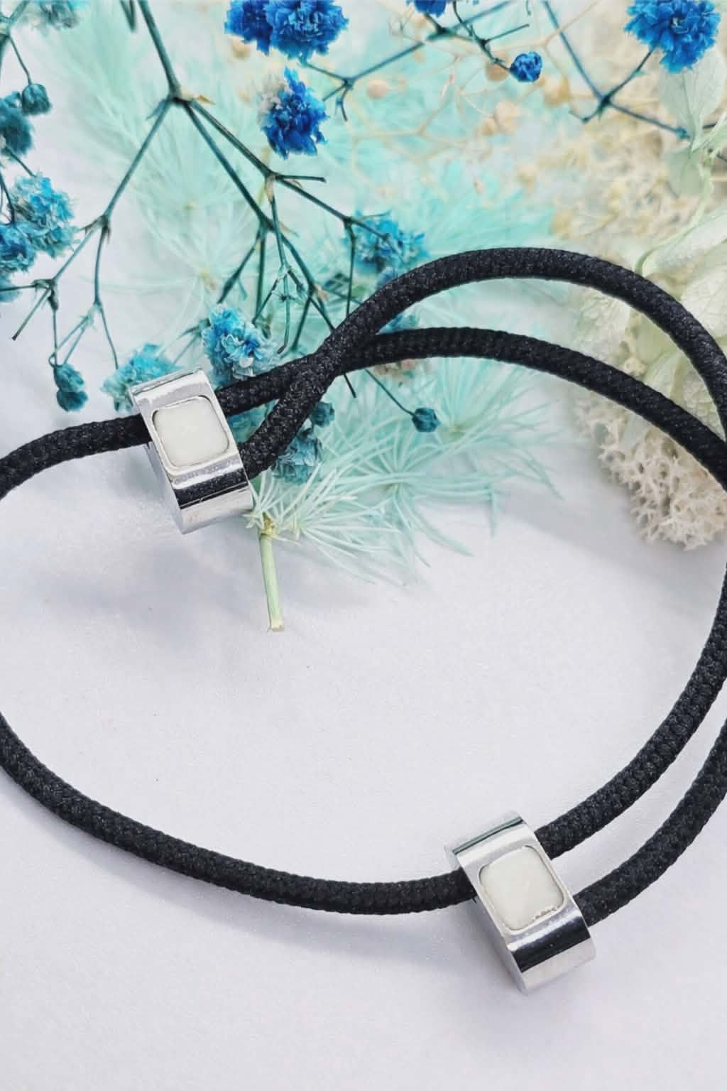 Adjustable stainless steel bracelet with two 5x5mm bezels filled with white breastmilk resin, engraved with initials