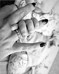 Close-up black and white photo of baby holding parent’s finger symbolising connection and memory