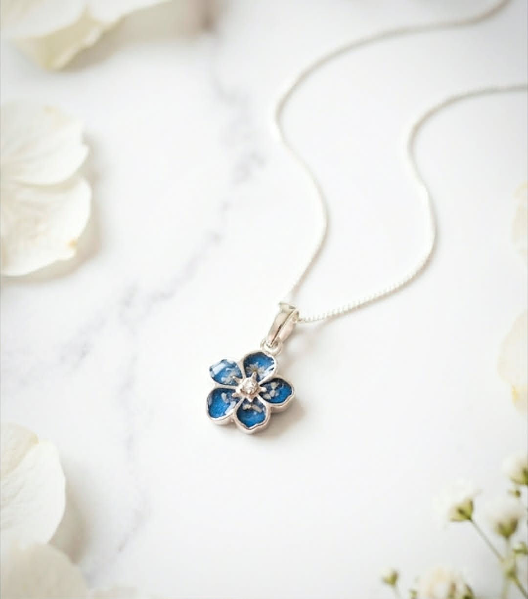Evolet ashes necklace in sterling silver flower shape with ashes set in blue resin and crystal centre