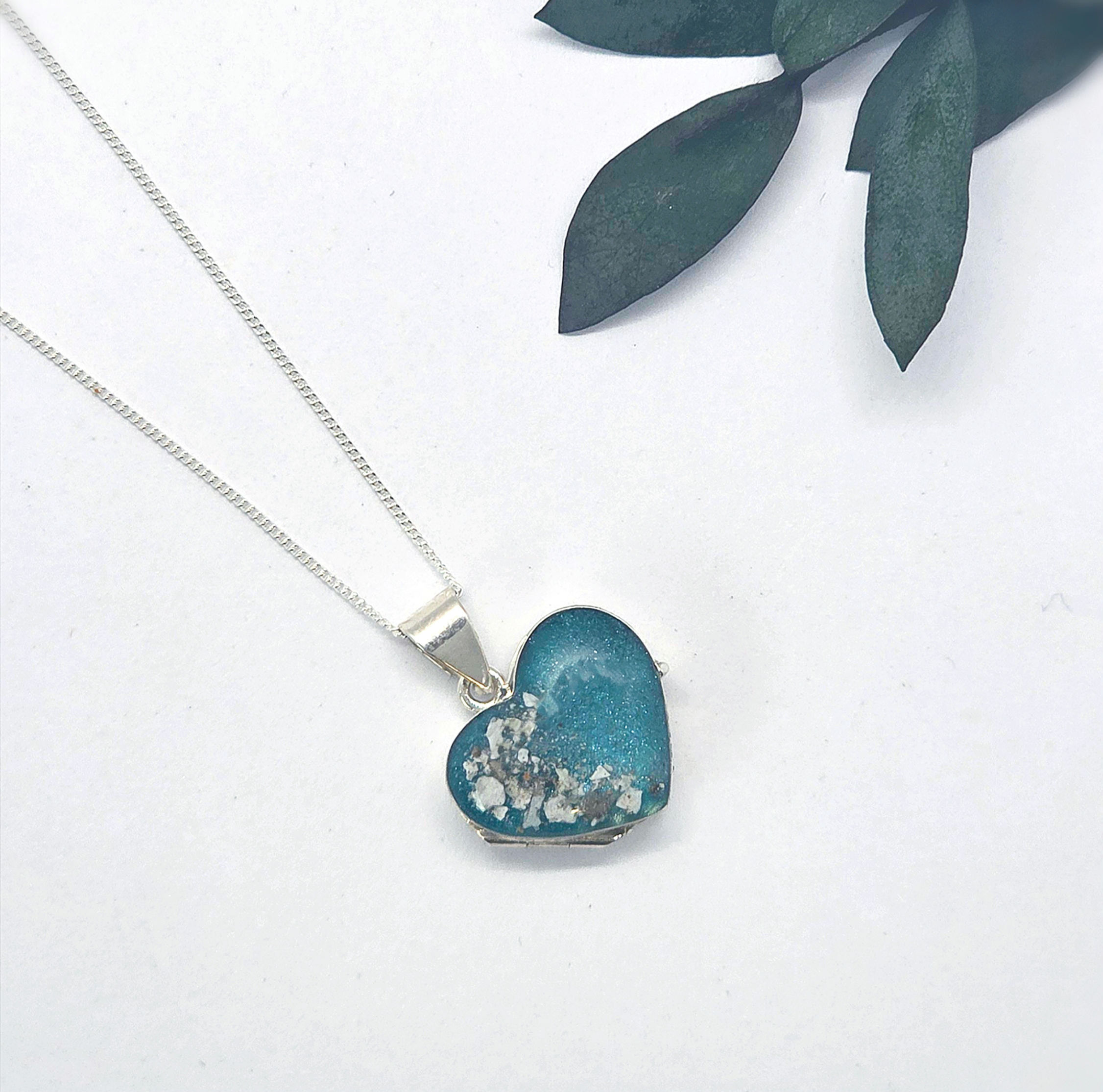 Memorial ashes locket in sterling silver with circular inclusion front and matching chain, styled on neutral background.