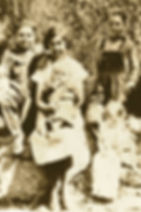 Sepia-toned family portrait outdoors. Nora Callahan sits with a baby "Buddy" who is sucking four of his fingers on her lap, flanked by Earl and Lorne wearing overralls and little Merna holding a doll and looking down at her lap.