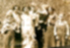 Vintage photo of a the Callahan family in 1934 at Shoup. They are outdoors, in casual attire,, but the girls, Eleanor and Lois are dressed up. Ed Callahan is holding his grandson " Buddy" Aaron. They stand in front of tall brush growing on a hillside, all smiling faintly aside from Earl who is trying to look seriously grown up at the age of twelve.