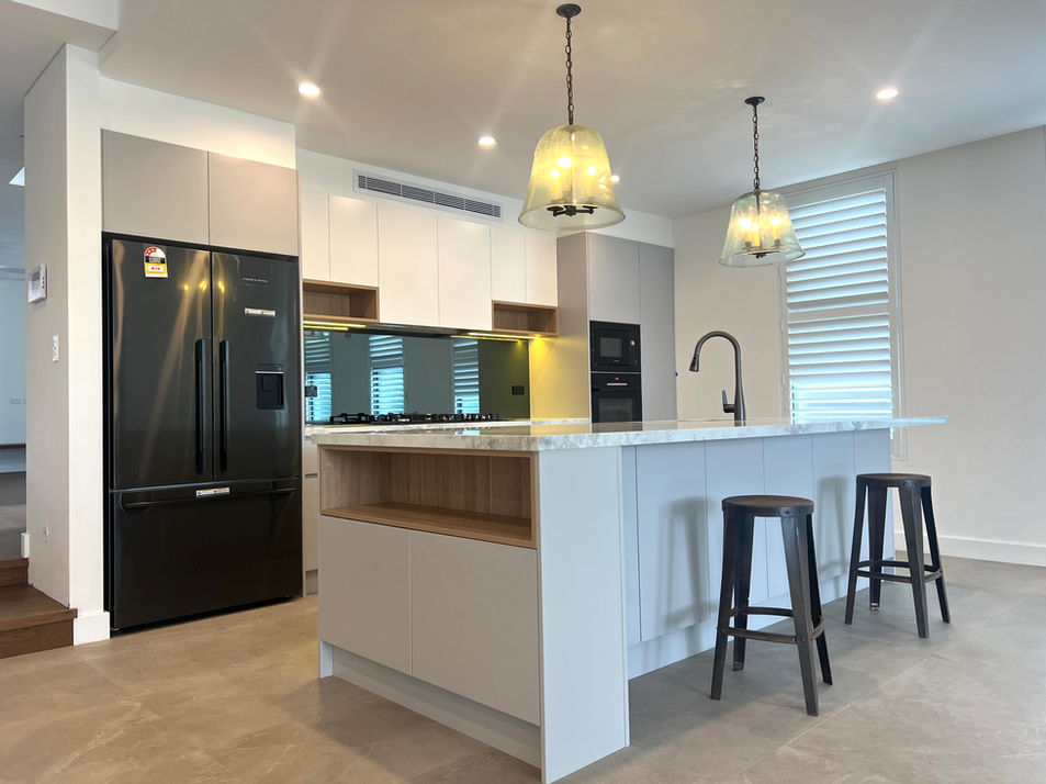 Luxury Chatswood kitchen with a large stone island, custom light grey cabinetry, timber display shelving, and bespoke joinery in Sydney.