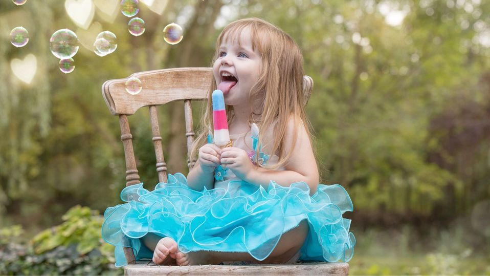 A young girl enjoying a popsicle during a family portrait session at Chalet Studio & Gardens in Windsor