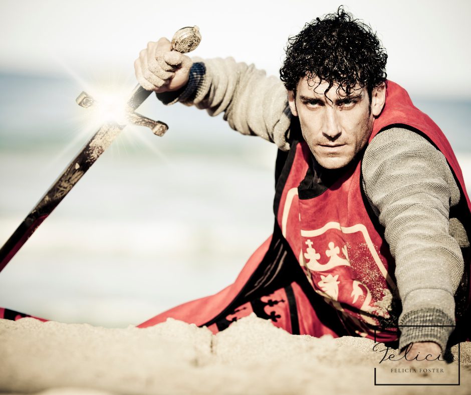 Man in a red medieval costume holds a sword with glowing blade on a sandy beach, intense expression, sea in background, text bottom right.