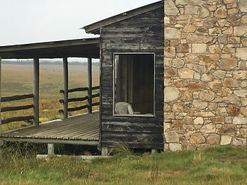 Historical photo of Smokewood Garzón's porch before renovation, showing its classic rural architecture with weathered wooden siding and traditional stone chimney