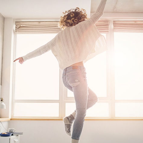 Person journaling by a window in soft natural light, reflecting on emotions in a calm and grounded environment.