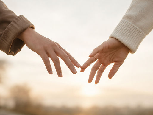 Close-up of two hands gently separating with fingertips barely touching in soft natural light, symbolizing heartbreak, loss, and emotional disconnection after a relationship ends.