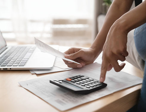 African woman holding paper bills using calculator, close up vie_edited.jpg