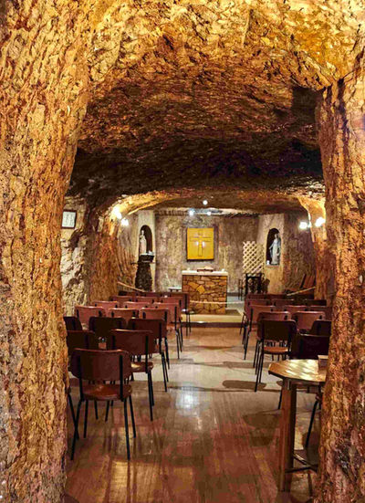 Chapel carved into rock with wooden chairs and altar