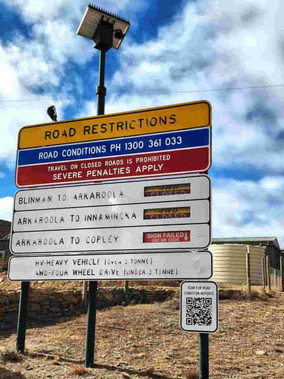 Road Restrictions sign with phone 1300 361 033, prohibiting travel on flooded roads.