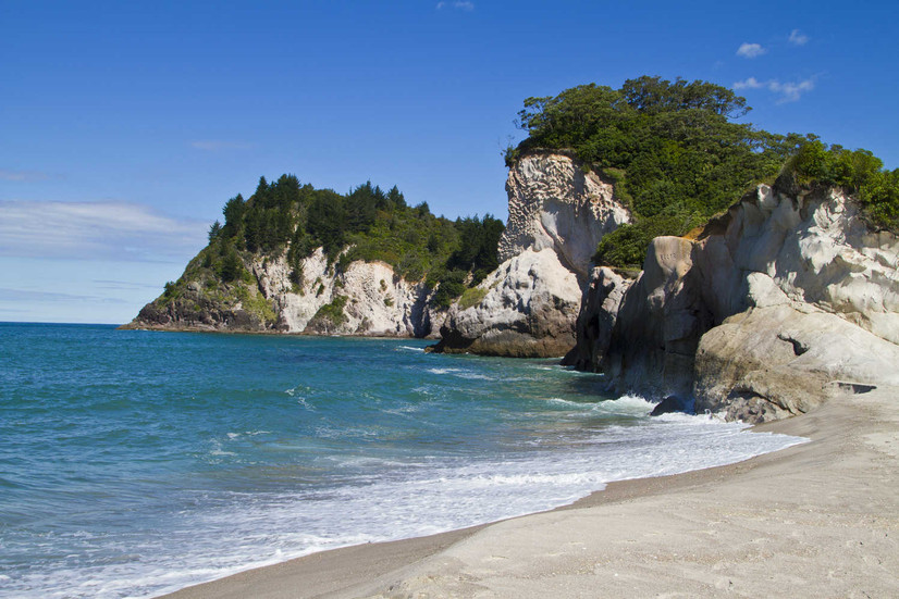 White sand, rocky headlands framing the crescent shaped New Chums beach, Coromandel Peninsula.j