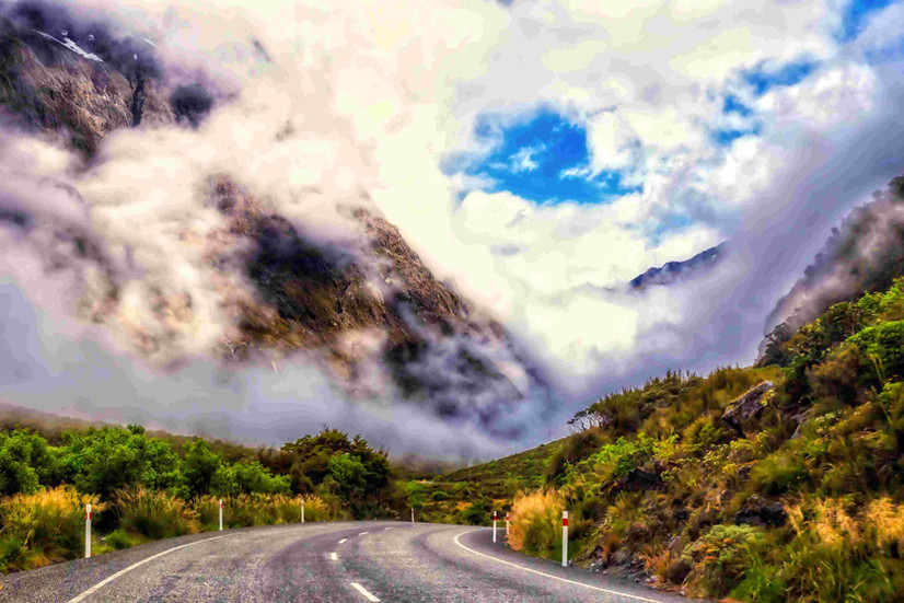 Roadside view of SH 94 to Milford Sound, winding, narrow with mountain ranges and glacial rivers