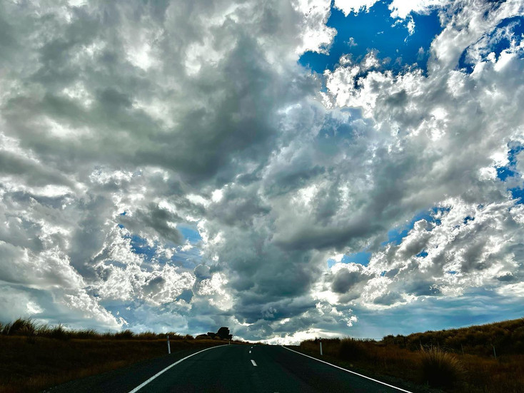 Road through outback under dramatic sky