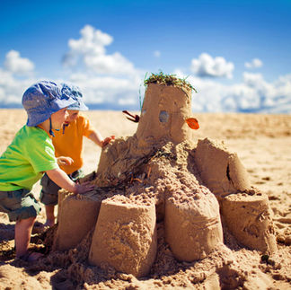 Two children building an elaborate sandcastle on a sunny beach