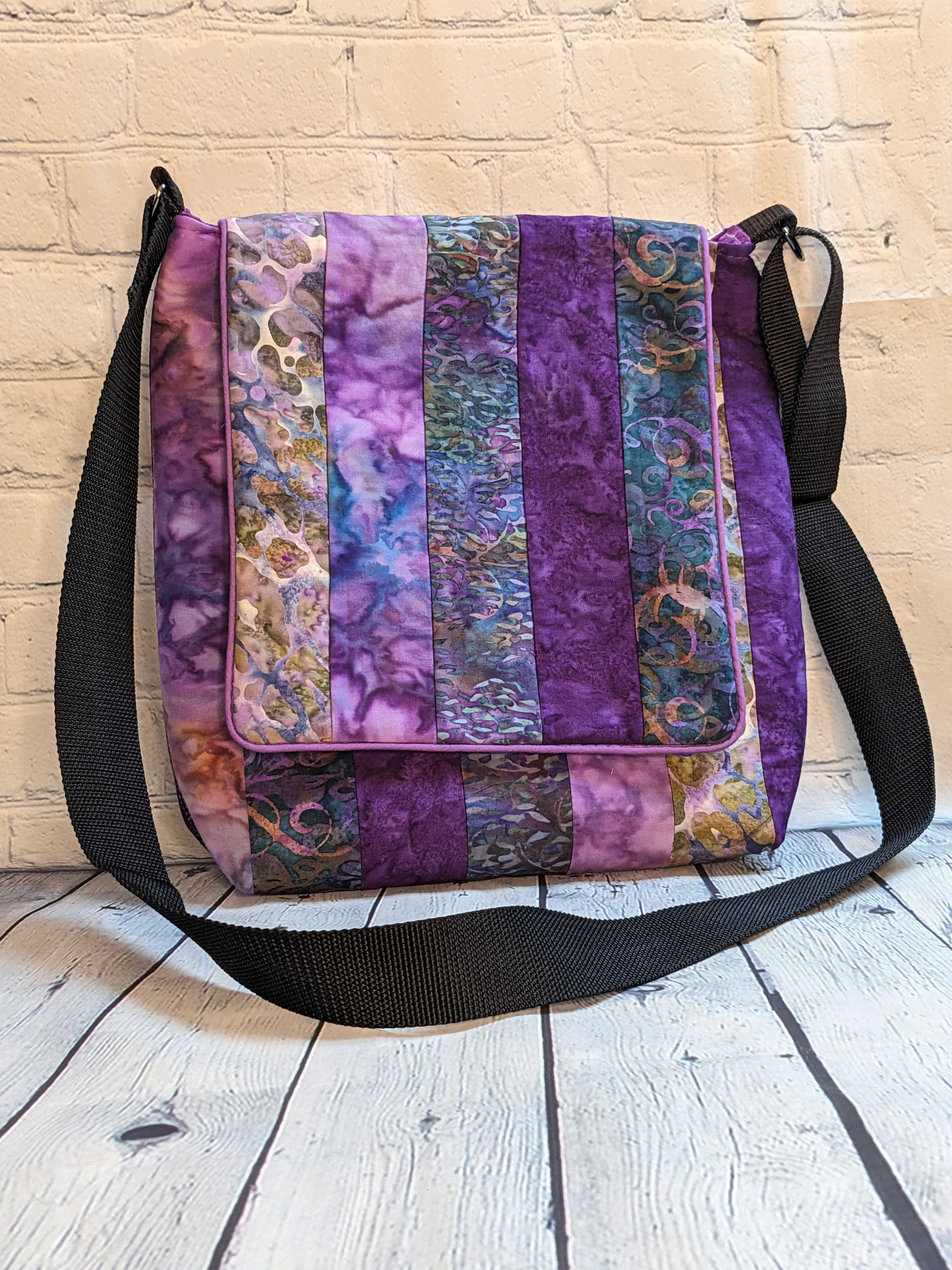 Large Messenger Bag - front view - Purple Dreams print, 100% Cotton, Color: Batik Purples/Lavender/Green, Special Features: Strip pieced, magnetic closure, 5 pockets, cotton webbing strap, color coordinated zippers, size: Size: 13" W x 14"L, JordynCherise 