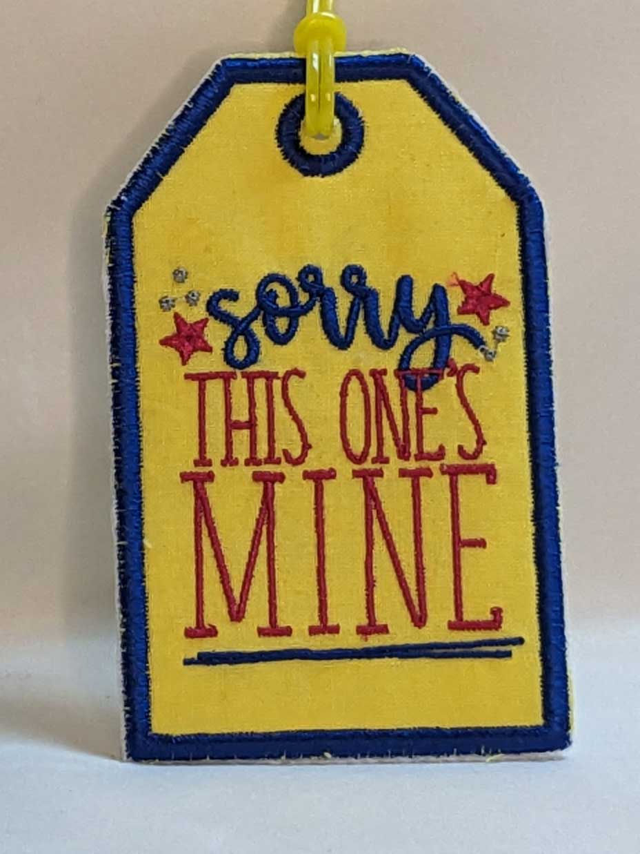 Thumbnail: Embroidered Luggage tag with message "Sorry This One's Mine!" Main Background Color:   Yellow, Fabric: 100 % Cotton, Vinyl, Size: 3 x 4-1/2", Special Features: Embroidered lettering, design and borders, vinyl on back for name card, Vinyl loop attachment to hook to luggage, JordynCherise