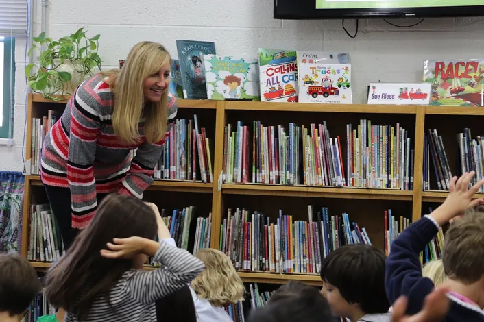 Author Sue Fliess engages with elementary students in a library during a school visit.