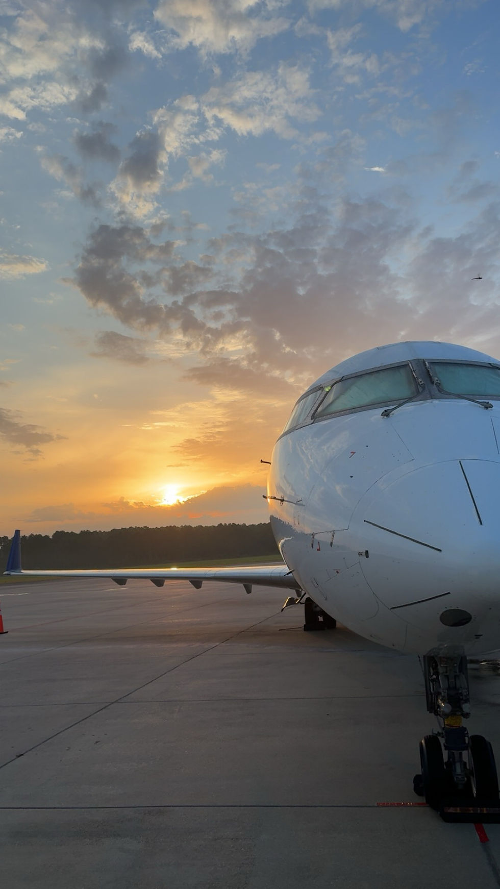 Front view of a white airplane at sunset on a runway