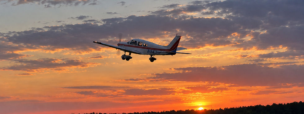 Small airplane flying during a sunset near an airport