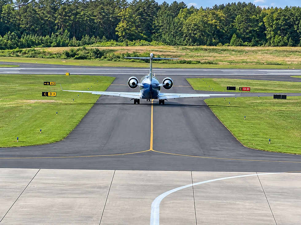 Private jet taxiing on a runway toward a forest.