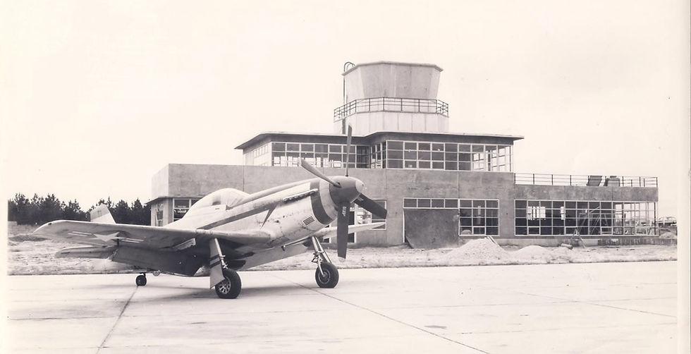 Vintage propeller plane parked near an airport tower.