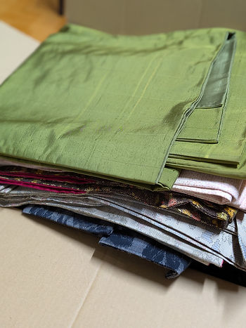 Stack of vintage Oshima Tsumugi silk fabrics for upcycling (100年前のヴィンテージ紬の反物)