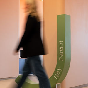 Person walking past a sign saying "Hey Parent!"