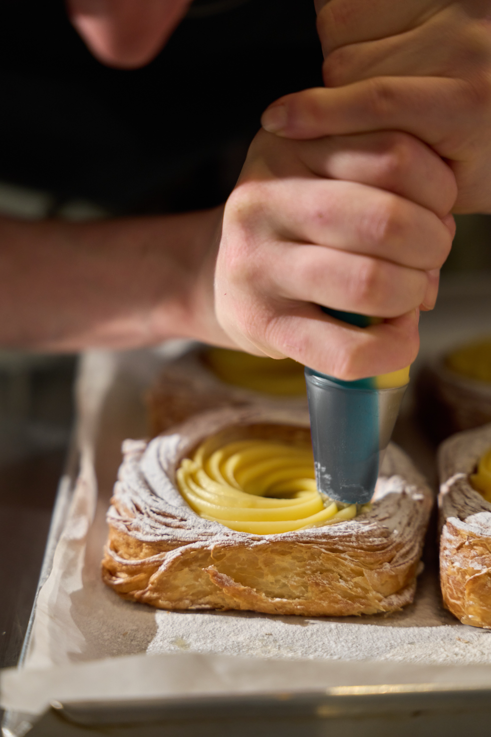 Person piping cream onto a pastry.